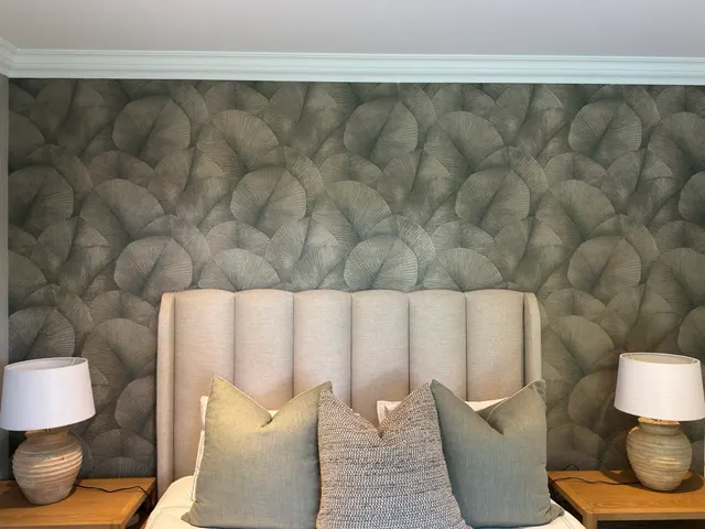 Printed botanical wallpaper behind an upholstered headboard