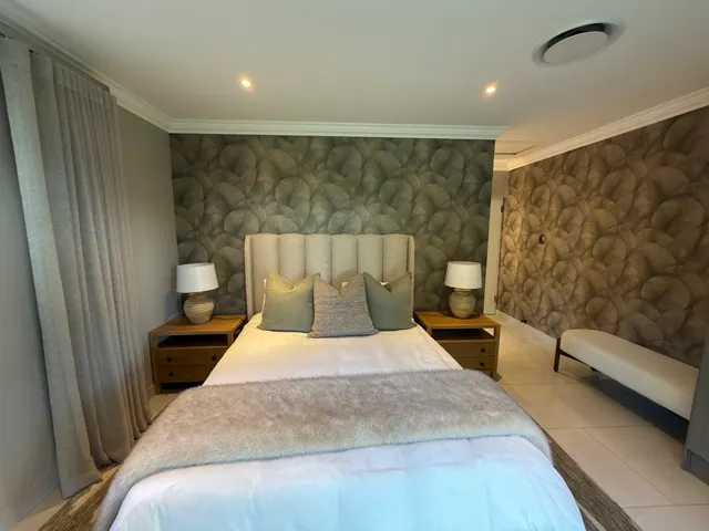 Printed leaf-pattern wallpaper forming a bedroom feature wall