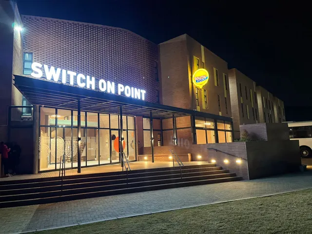 Illuminated Switch On Point lettering across a brick facade at night